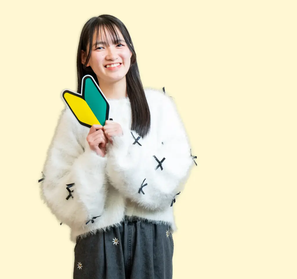初心者マークを持つ女生徒 背景クリームイエロー